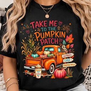 Peut inclure: Un t-shirt noir avec un motif représentant un pick-up orange rempli de citrouilles, de tiges de maïs et de feuilles d'automne. Le texte indique "TAKE ME TO THE PUMPKIN PATCH" avec des panneaux "HAYRIDES", "CIDER", "PUMPKIN PATCH" et une tasse "PUMPKIN SPICE & EVERYTHING NICE".