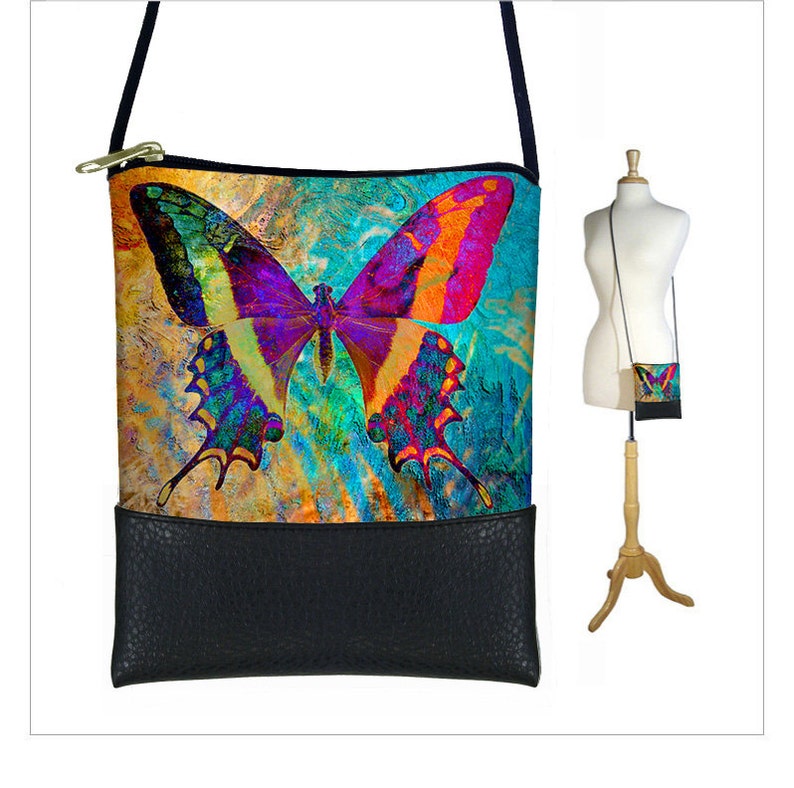 May include: A colorful butterfly print crossbody bag with a black faux leather bottom. The bag has a zipper closure and a long adjustable strap.