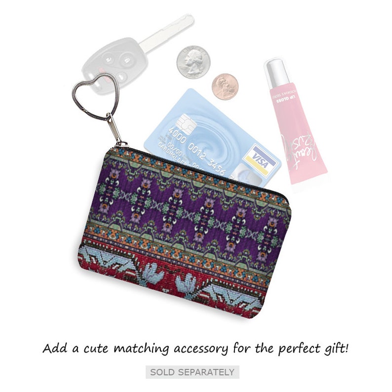May include: A small purple and red patterned coin purse with a zipper closure. The purse is open and has a credit card, a key, and a tube of lip gloss inside.
