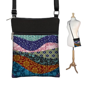 May include: A black crossbody bag with a zipper closure and a colorful patterned flap. The pattern features a variety of colors, including blue, green, red, and yellow, and is made up of different geometric shapes and designs.