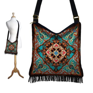May include: A turquoise, orange, and brown patterned crossbody bag with black fringe. The bag has a black adjustable strap.