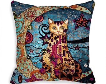 May include: A decorative throw pillow with a colorful, abstract design featuring a cat sitting on a crescent moon. The cat is patterned with geometric shapes and stars. The background is a blue and brown color with a swirling pattern.