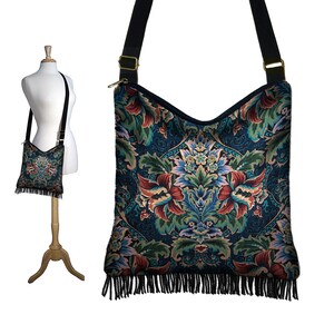 Puede incluir: Un bolso bandolera negro con un dise&ntilde;o de tapicer&iacute;a floral y flecos negros. El bolso tiene una correa larga ajustable.