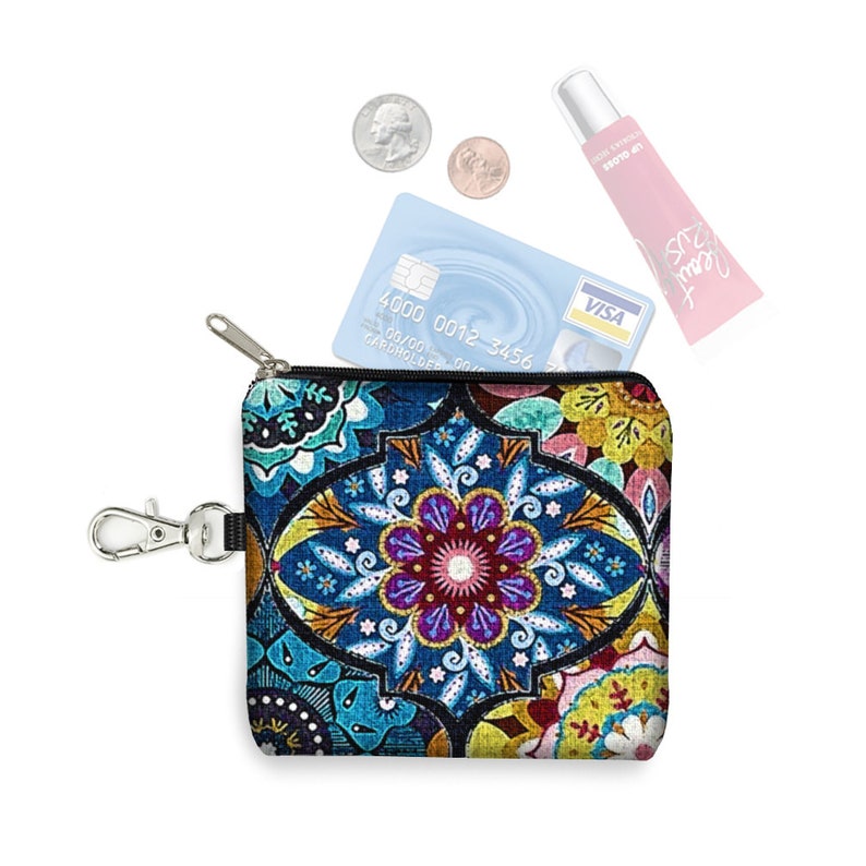 May include: A small zippered pouch with a colorful mandala design. The pouch has a silver zipper and a silver clip. The pouch is open and a credit card with the Visa logo is visible inside. The credit card number is 4000 0012 3456. There are also two coins and a tube of lip balm visible.