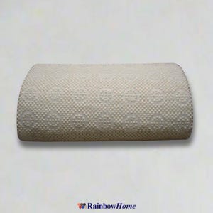 May include: A white, rectangular pillow with a raised, patterned surface. The pillow is slightly curved and has a soft, plush texture.