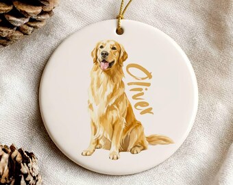 May include: A round, white ceramic ornament featuring a golden retriever illustration. The dog is sitting with its tongue out. The name "Oliver" is written in gold script. A gold string is attached for hanging.