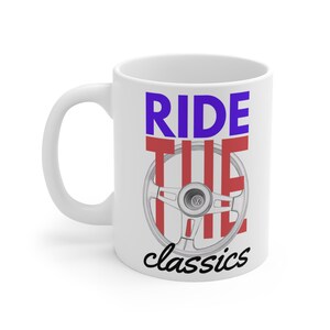Può includere: Tazza in ceramica bianca con la scritta "RIDE THE classics" in blu, rosso e nero. Il design include un volante. La tazza ha un manico curvo.
