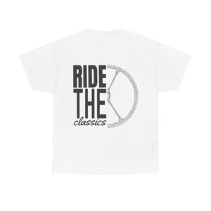 Può includere: T-shirt bianco con la scritta "RIDE THE classics" in nero. Una grafica di ruota di bicicletta è sul lato destro. La maglietta è realizzata in un materiale morbido e confortevole.