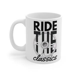 Può includere: Tazza in ceramica bianca con la scritta nera "RIDE THE classics". Al centro del testo è presente una grafica in bianco e nero di un volante. La tazza ha un manico bianco.