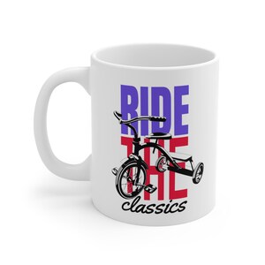 Può includere: Tazza in ceramica bianca con un'illustrazione in bianco e nero di un triciclo. Le parole "RIDE THE classics" sono stampate in blu, rosso e nero.