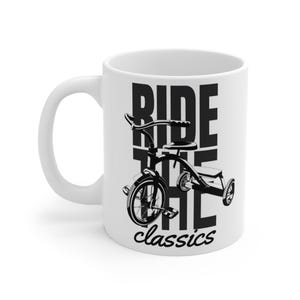 Può includere: Tazza in ceramica bianca con un'illustrazione in bianco e nero di un triciclo e la scritta "RIDE THE classics". La tazza ha un manico curvo e una finitura lucida.