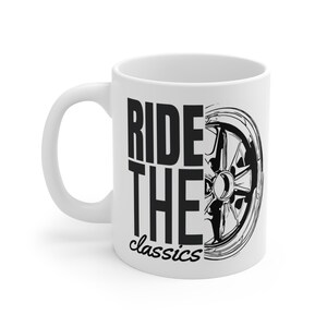 Può includere: Tazza in ceramica bianca con una grafica nera di una ruota di auto e le parole "RIDE THE classics". La tazza ha un manico curvo e una finitura lucida. Il design è sulla parte anteriore della tazza.