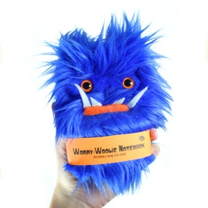 May include: Blue fuzzy monster plush toy with orange teeth and eyes. The toy has a label that reads "Worry Woolie Notebook" and "Everything is going to be alright".