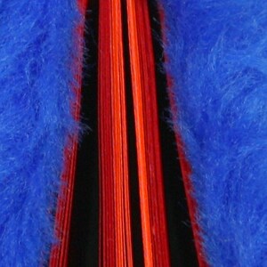 May include: A close-up of a red and orange book spine with a blue fuzzy cover. The book is closed and the spine is visible.