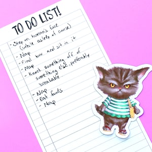 May include: A white to-do list with a handwritten list of tasks, including "Step on human's face (while asleep of course)." and "Nap". A grumpy cat sticker is on the list.