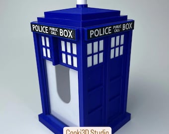 May include: A blue 3D-printed Police Box, a replica of the iconic British phone booth. The box features white window panels and the words "POLICE PUBLIC CALL BOX" in white lettering. The design includes a white top and base.