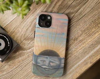 May include: A phone case featuring a surrealist painting of a sun with a face, set against a pastel sky. The artwork includes shades of blue, pink, and yellow. The case is on a wooden surface.