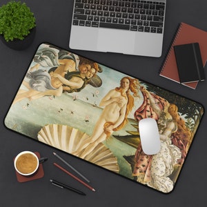 May include: A rectangular mouse mat featuring a print of Sandro Botticelli's "The Birth of Venus." The artwork depicts Venus emerging from a seashell, with figures of Zephyr and Chloris. The mouse mat has a black border and is placed on a dark surface.