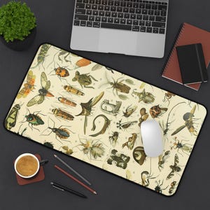 Pode incluir: Um mousepad retangular com uma ilustração vintage de vários insetos em tons de bege, verde, laranja e castanho. O mousepad tem uma borda preta e inclui um mouse branco, um laptop e material de escritório.