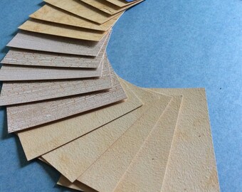 May include: A fan of small, rectangular samples in various colors and textures. The samples include shades of blue, beige, and brown, with patterns like brick, stone, and textured surfaces. The samples are arranged in a semi-circle on a blue background.