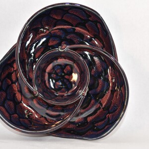 May include: A ceramic serving dish with three sections, each with a different swirling pattern of dark blue and burgundy glaze.