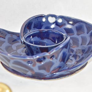 May include: A blue ceramic serving dish with a smaller bowl attached. The dish has a swirl design and a glazed finish.