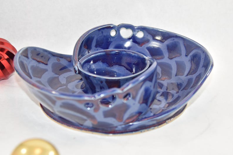 May include: A blue ceramic serving dish with a smaller bowl attached. The dish has a swirl design and a glazed finish.