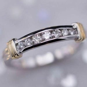 May include: A thin gold and silver band with a row of small diamonds set in a channel setting.