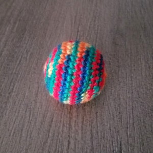 May include: A colorful crocheted ball with stripes of red, orange, yellow, green, blue, and white.