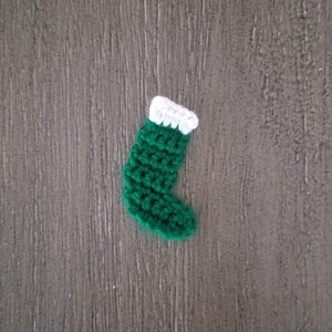 May include: A small green crocheted stocking with a white crocheted cuff.