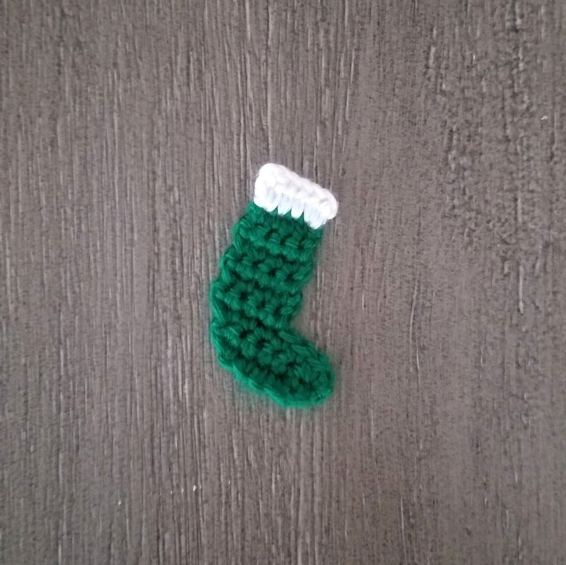 May include: A small green crocheted stocking with a white crocheted cuff.