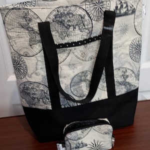 Könnte beinhalten: Ein Set aus Tragetasche und kleinem Münzbeutel. Die Tragetasche hat einen cremefarbenen Stoff, der mit Vintage-Weltkarten und Windrosen bedruckt ist, mit schwarzen Griffen und einem schwarzen Boden. Der Münzbeutel hat das gleiche Kartendesign.