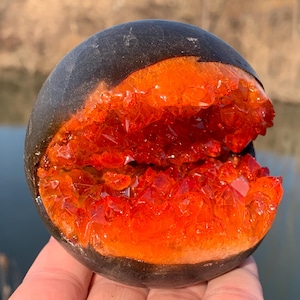 May include: A geode with a black exterior and a bright orange interior filled with crystals.