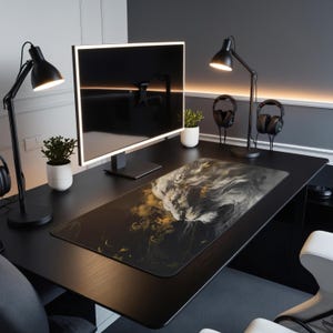 May include: A black desk with a black computer monitor, two black desk lamps, and a black and white lion-themed mouse mat. The desk has a black surface and a black frame. There are two potted plants on the desk.