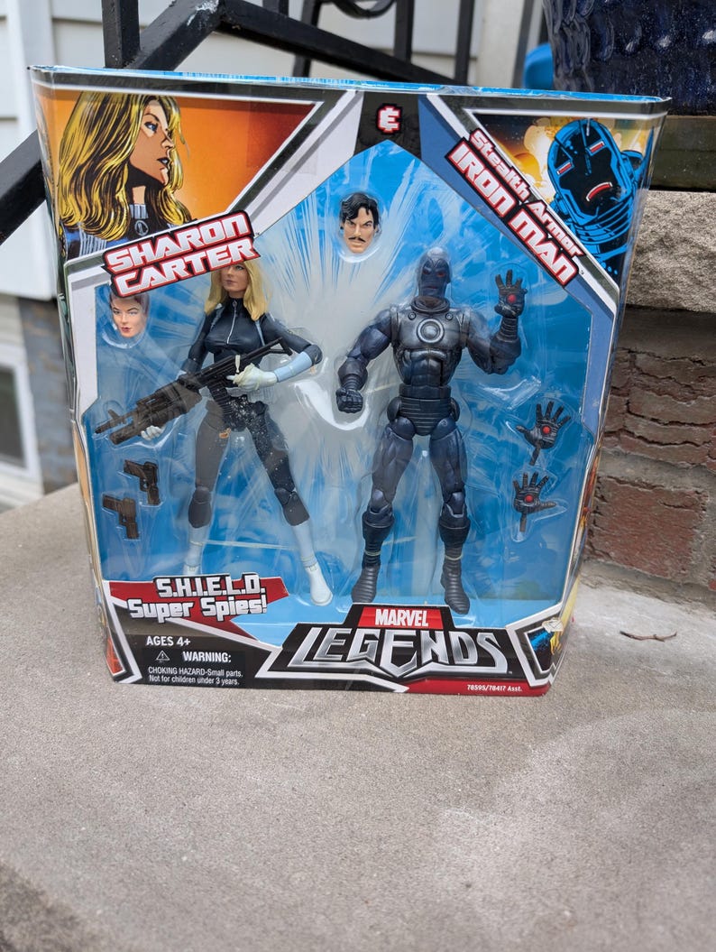 Puede incluir: Un set de figuras de acci&oacute;n Marvel Legends con Sharon Carter y Iron Man con armadura sigilosa. Las figuras est&aacute;n empaquetadas en una caja azul y blanca con el logotipo de Marvel Legends. La caja tambi&eacute;n incluye el texto "S.H.I.E.L.D. Super Spies!" y "Edad 4+ Advertencia: Riesgo de asfixia - Piezas peque&ntilde;as. No apto para ni&ntilde;os menores de 3 a&ntilde;os."