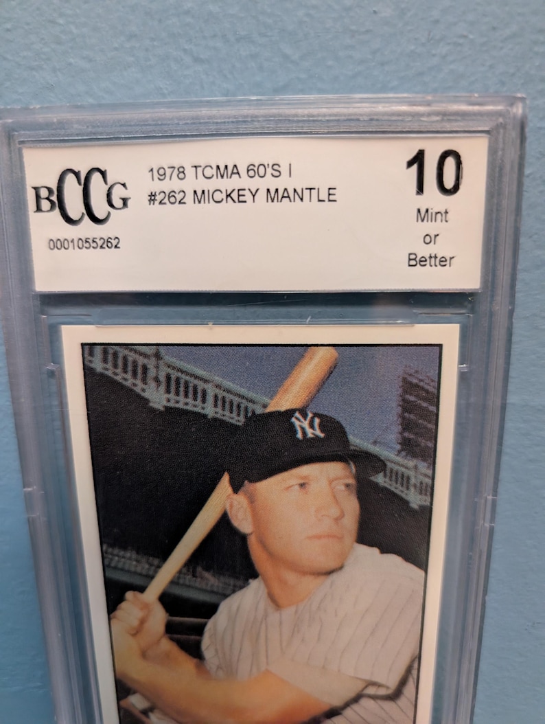 May include: A graded baseball card featuring Mickey Mantle. The card is encased in a protective holder and is graded a 10, labeled "Mint or Better." The card is from the 1978 TCMA 60's I series, card #262.