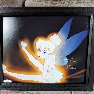 May include: A framed print of Tinker Bell from the Disney film Peter Pan. The print is signed by Margaret Kerry, the live-action model for Tinker Bell. The signature reads "Margaret Kerry, for Bell".