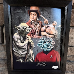 May include: A framed print featuring a collage of characters from popular science fiction franchises. The print includes Yoda from Star Wars, a creature from the film 'The Last Starfighter', and a character from Star Trek. The print is signed by the artist.