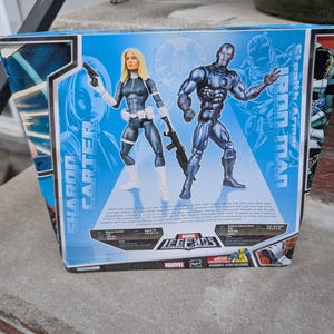 Puede incluir: Embalaje de figura de acci&oacute;n de la serie Marvel Legends con Sharon Carter y Iron Man en armadura sigilosa. El embalaje es azul y rojo con el logotipo de Marvel Legends. La parte posterior de la caja incluye informaci&oacute;n sobre los personajes y sus habilidades.