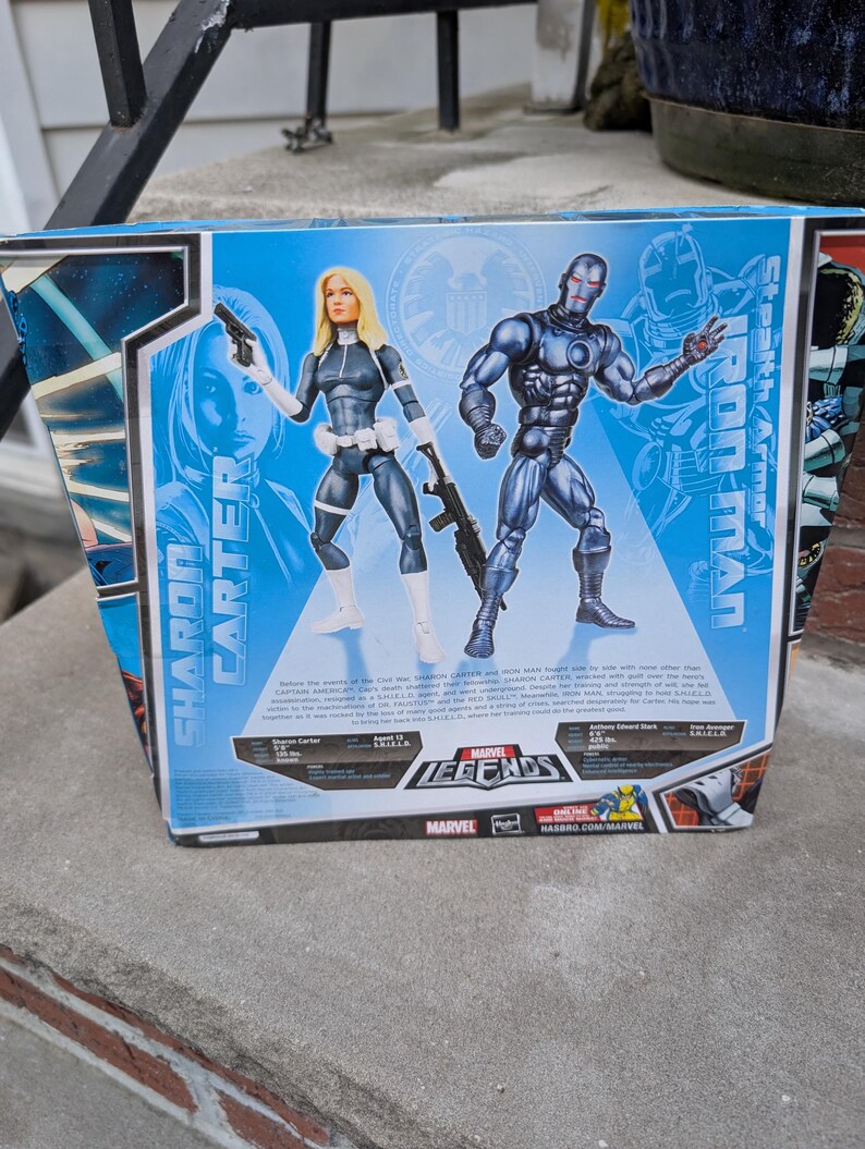 Puede incluir: Embalaje de figura de acci&oacute;n de la serie Marvel Legends con Sharon Carter y Iron Man en armadura sigilosa. El embalaje es azul y rojo con el logotipo de Marvel Legends. La parte posterior de la caja incluye informaci&oacute;n sobre los personajes y sus habilidades.