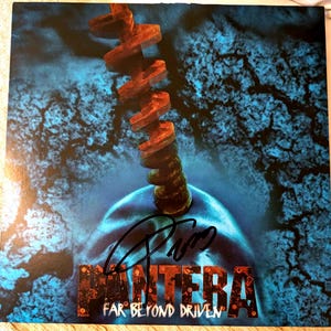 May include: A black vinyl record with a blue and black image of a rusty metal screw. The record is signed "Pantera" and the album title "Far Beyond Driven" is printed below the signature.