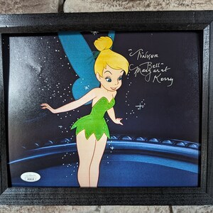 May include: Framed illustration of Tinker Bell, a fairy with green wings and a green dress, against a dark blue background with stars. The illustration is signed "Tinker Bell Margaret Kerry".