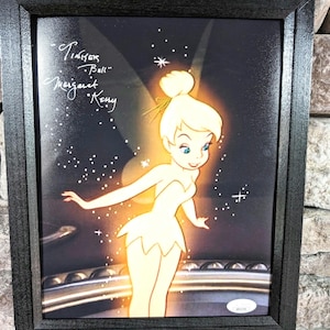 May include: A framed print of Tinker Bell, a Disney fairy, with a sparkling glow. The print is signed "Tinker Bell" and "Margaret Kerry".
