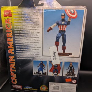 May include: Captain America action figure in a box. The figure is in a classic pose, holding his shield. The packaging features text about the character's origin and other Marvel characters. The box has a Disney tag.