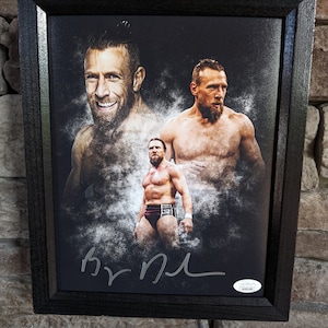 Könnte beinhalten: Ein schwarzer gerahmter Leinwanddruck mit einem Schwarzweißbild von drei Männern. Die Männer sind alle oben ohne und haben Gesichtsbehaarung. Das Bild ist verblasst und hat eine körnige Textur. Der Druck ist mit "By MJ" signiert.