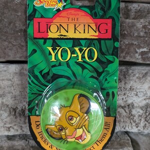 May include: A green and yellow yo-yo with a picture of Simba from Disney's The Lion King. The packaging says "Do Tricks & Stunts! Collect Them All!"