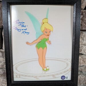 May include: A framed cel of Tinker Bell from the Disney movie Peter Pan. The cel is signed "Tinker Bell" and "Margaret Kerry".
