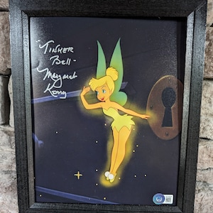 May include: A framed print of Tinker Bell, a fairy with green wings and a yellow dress, flying towards a keyhole. The print is signed "Tinker Bell - Margaret Kerry".