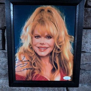 May include: A framed photograph of a woman with blonde hair, wearing a red top and smiling. The photo is signed "Love,  ____" in blue ink.