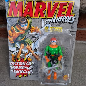 May include: A Marvel Super Heroes Dr. Octopus action figure in its original packaging. The figure is green and orange with four mechanical tentacles. The packaging features the Marvel logo and comic book-style artwork.